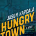 Hungry Town cover: title and author name in yellow and white letters with a blue tinted photograph of a factory town in the background
