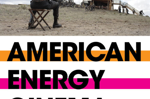 photo still from There Will Be Blood of a the back of a man sitting on a stool watching flames erupt some distance in front of him